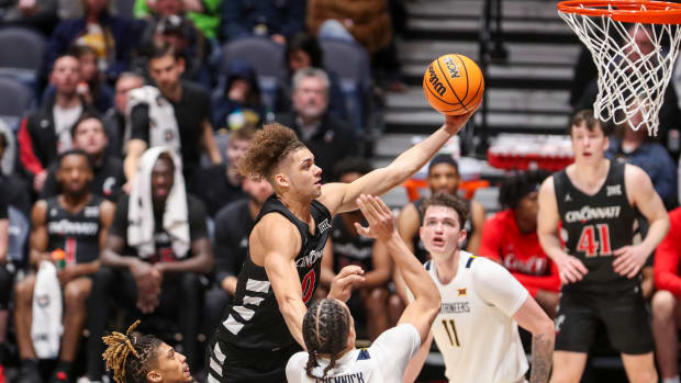 Jan 31, 2024; Morgantown, West Virginia, USA; Cincinnati Bearcats guard Dan Skillings Jr. (0) shoots in the lane over West Virginia Mountaineers forward Patrick Suemnick (24) during the second half at WVU Coliseum. Mandatory Credit: Ben Queen-USA TODAY Sports